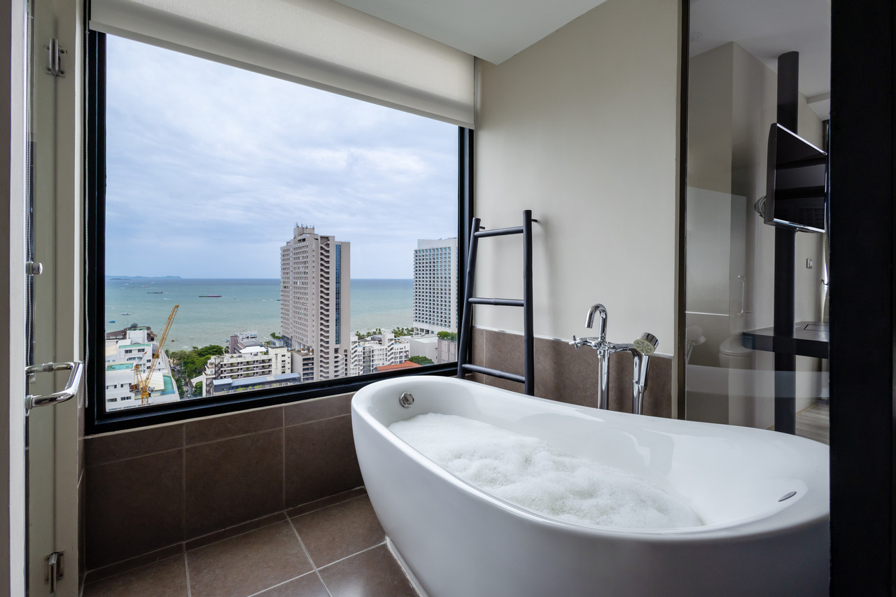 Bathroom with a freestanding tub and a panoramic window over the Pattaya skyline