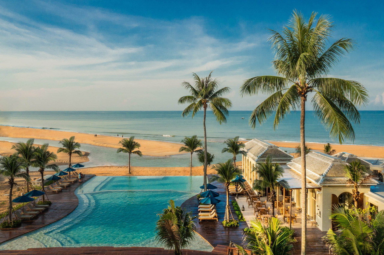 Aerial view of the horizon-edge pool at Devasom Khao Lak with the beach and Andaman Sea
