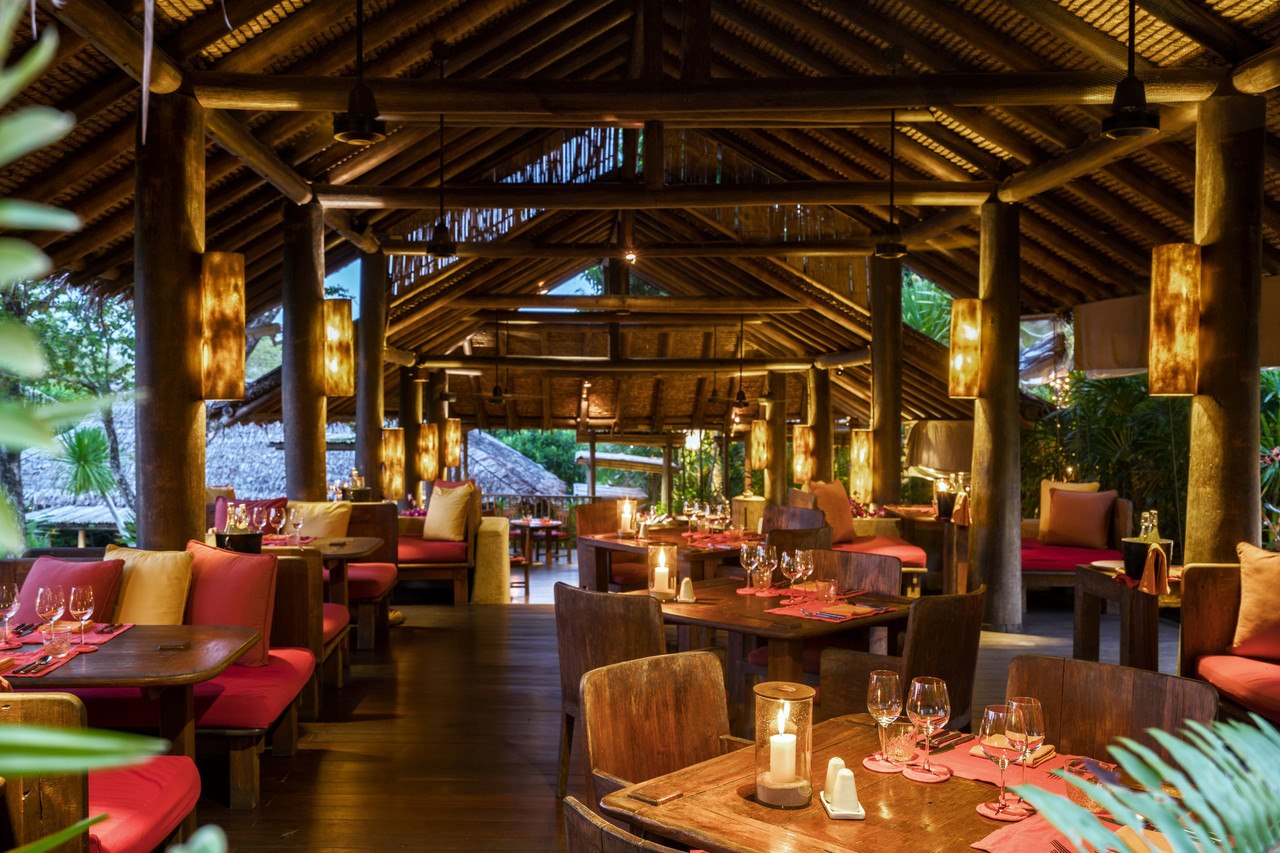 Thatched-roof restaurant interior with warm lighting and red cushions