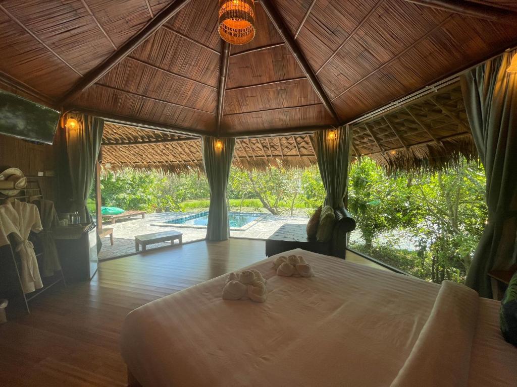 ห้องนอนโดมไม้ไผ่เปิดบานกระจกออกสู่สระว่ายน้ำส่วนตัวและวิวทะเลสาบ Baan Pak Pra Villa