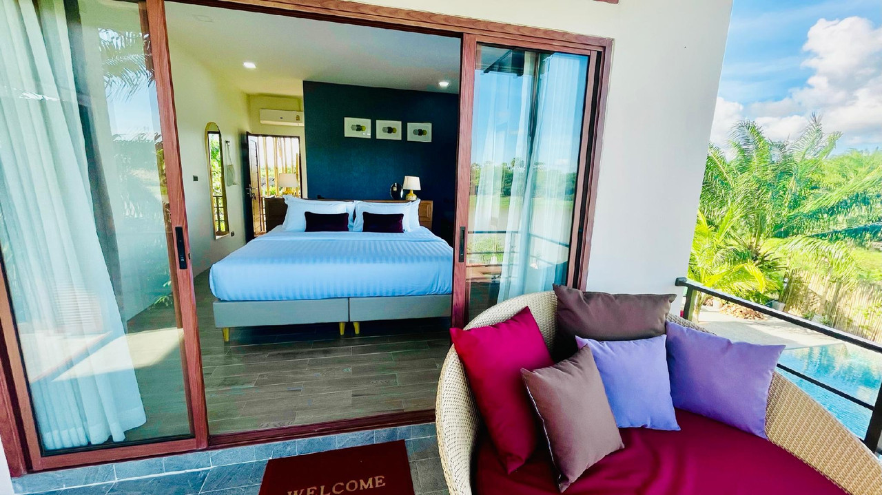 Deluxe River View room with a balcony daybed looking over Pakpra Canal