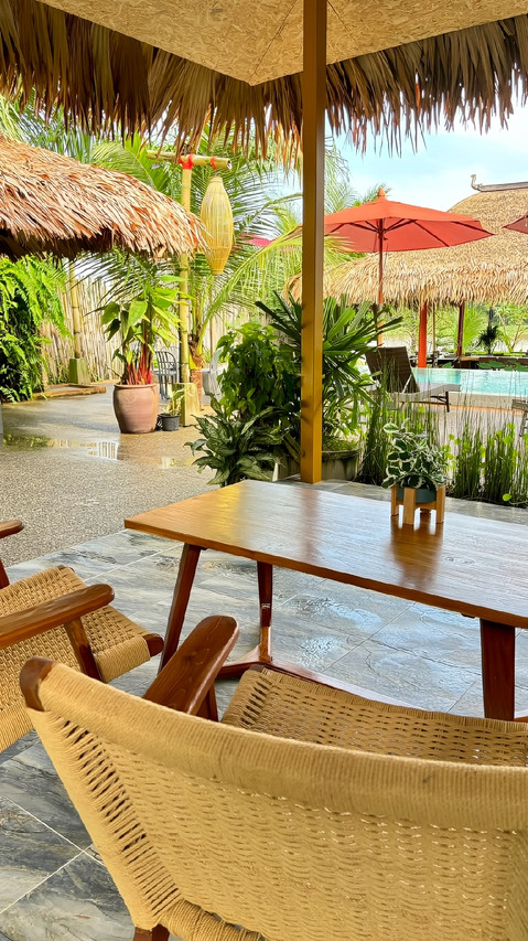 Garden lounge and dining terrace under thatched roofs at Canal Village Pakpra