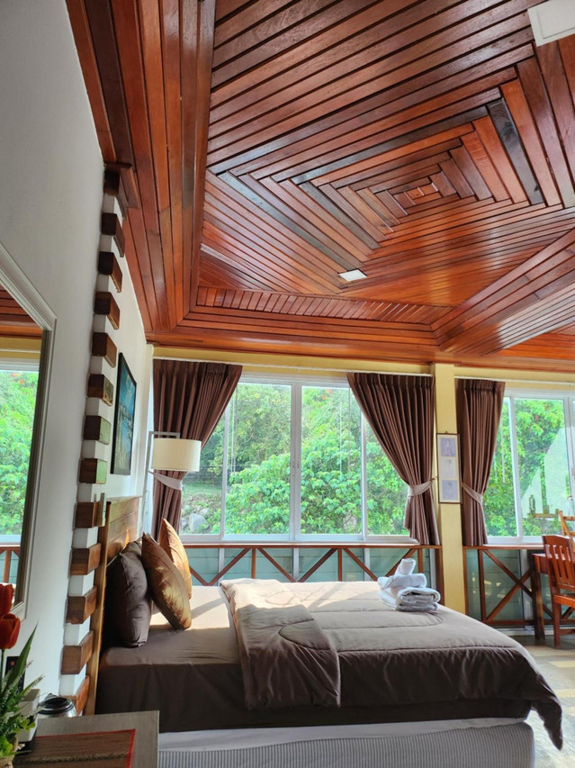 ห้อง Double วิวเขาของ Mountain View Guest House พัทลุง เพดานไม้สักลายก้นหอย เตียงใหญ่ ผ้าม่านสีน้ำตาล หน้าต่างบานใหญ่มองเห็นเขาเขียวด้านนอก