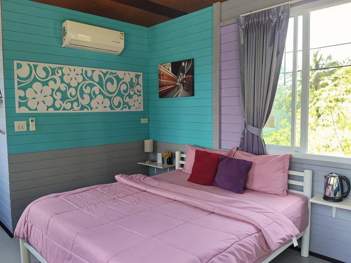 ห้องพักโทนเขียวเทอร์ควอยซ์-ม่วงของ Mountain View Guest House พัทลุง แอร์ติดผนัง ลายฉลุดอกไม้สีขาว เตียงผ้าปูสีชมพู กาต้มน้ำ หน้าต่างมองเห็นต้นไม้เขียว