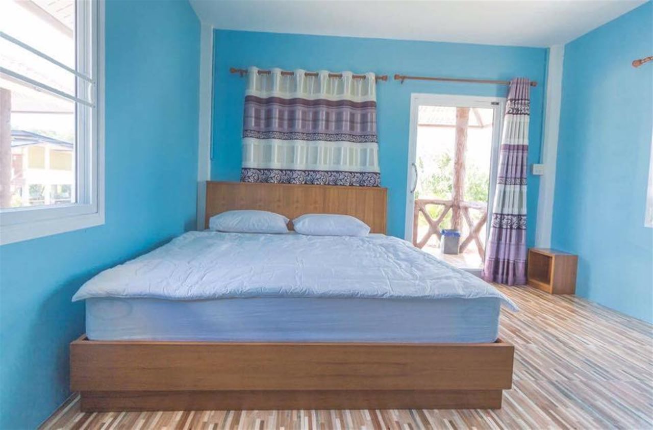 Blue-walled guest room with a wooden bed and a door to a private balcony