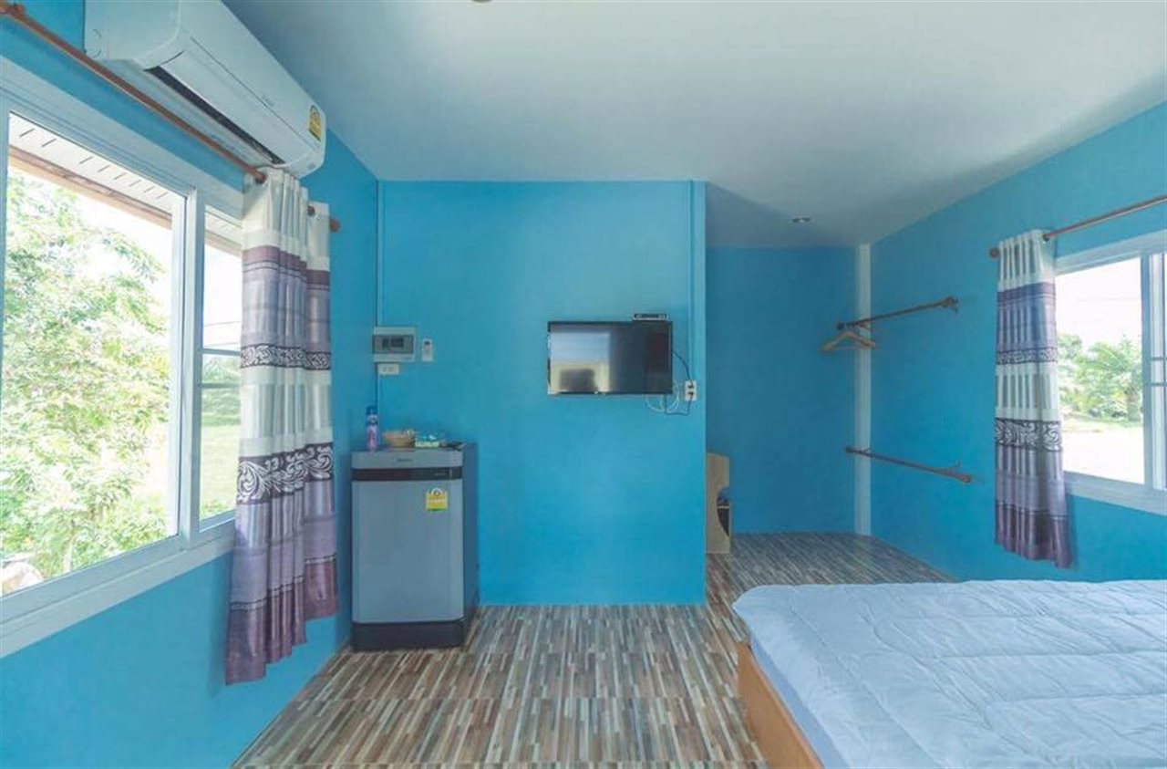 Guest room with air-conditioning, a fridge and a TV, looking out to greenery