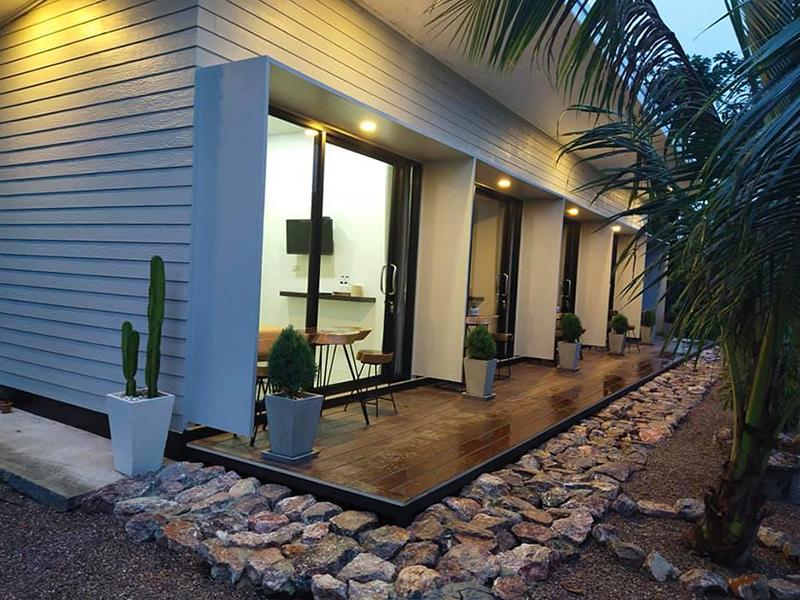 แถวห้องพักสไตล์โมเดิร์นบานกระจก ระเบียงไม้ โต๊ะนั่งเล่นหน้าห้อง Suan Chumchuen Resort