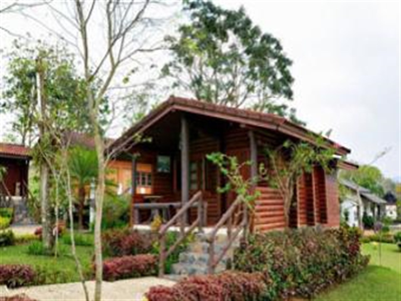 Standalone wooden cabin with a front veranda among gardens on Khao Kho