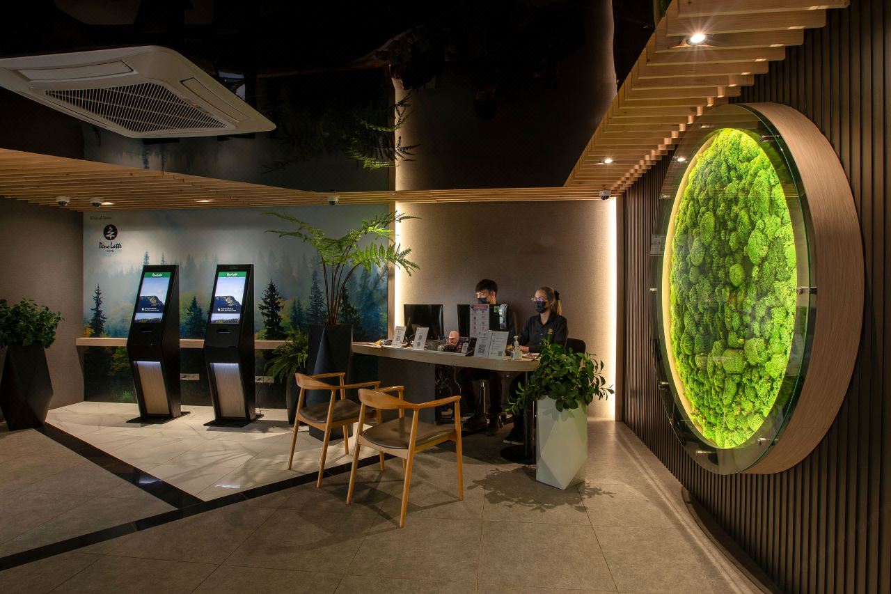 Pino Latte lobby with self check-in kiosks and a circular moss-art wall feature