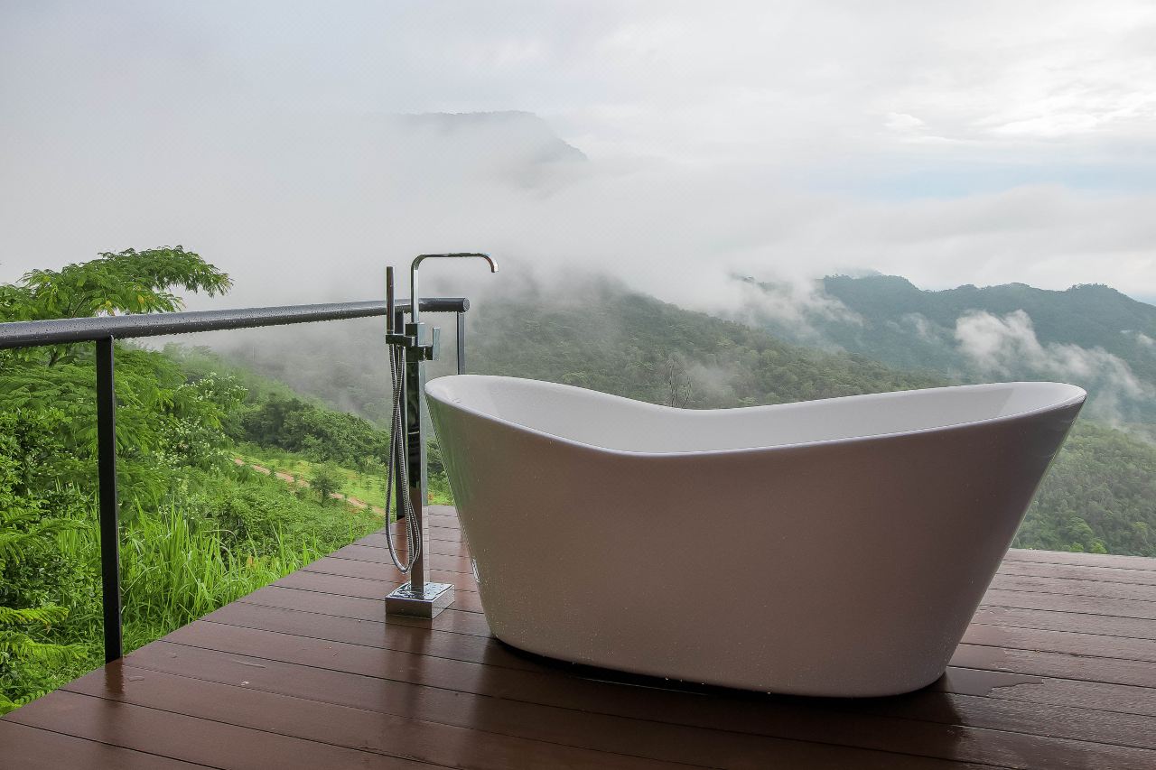 Outdoor bathtub on a wooden balcony deck overlooking the misty Khao Kho mountains