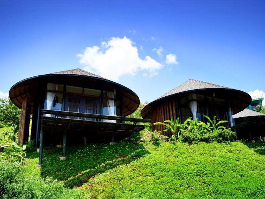 Cabins lining the ridge with a concrete path running down into the wide valley view at The Sense View Talaymok, Khao Kho