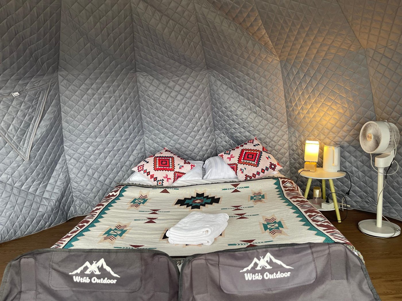 Inside a dome tent — bed with tribal-pattern bedding, lamp and fan, on Phu Thap Boek