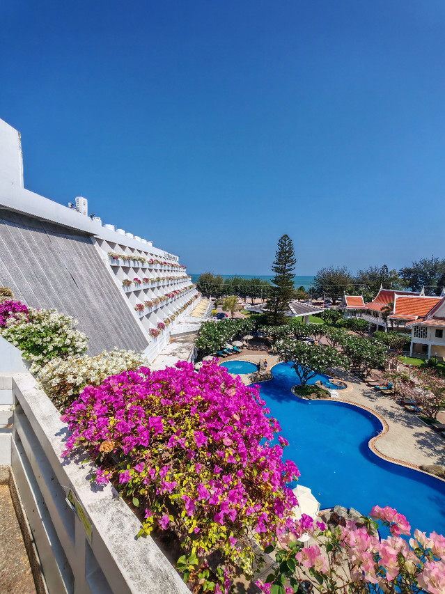 View from a guest-room balcony over the pool, bougainvillea and Cha-am sea