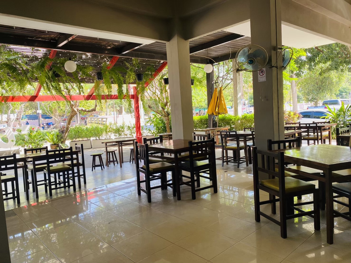 Semi-open dining area with wooden tables and ceiling fans at Sun Hotel Phetchaburi