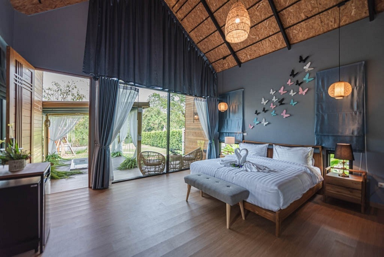 High-gabled villa interior with butterfly wall art opening onto the riverside garden at The Tree Riverside