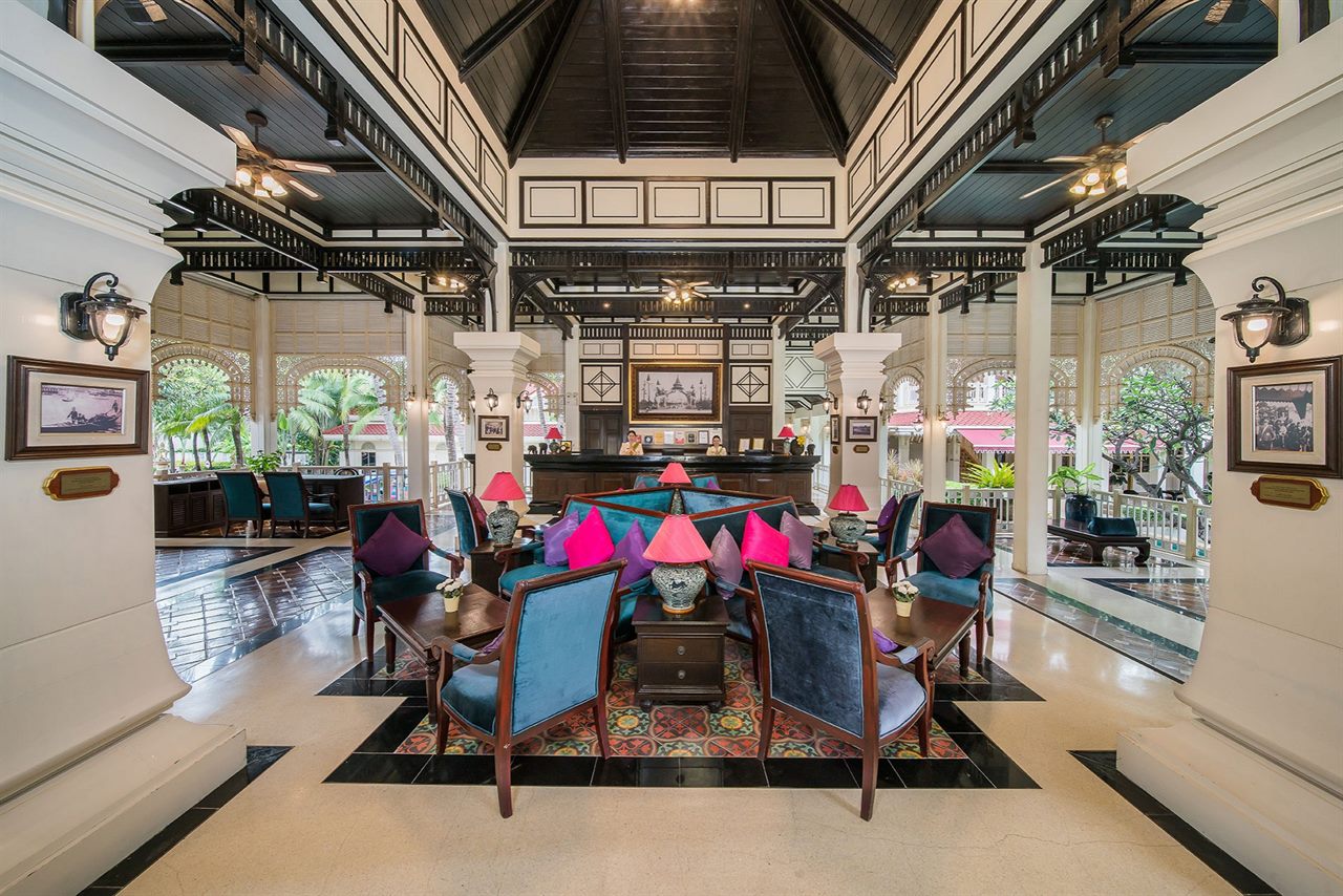 High timber-ceilinged Thai-Colonial lobby with white pillars and blue and pink armchairs