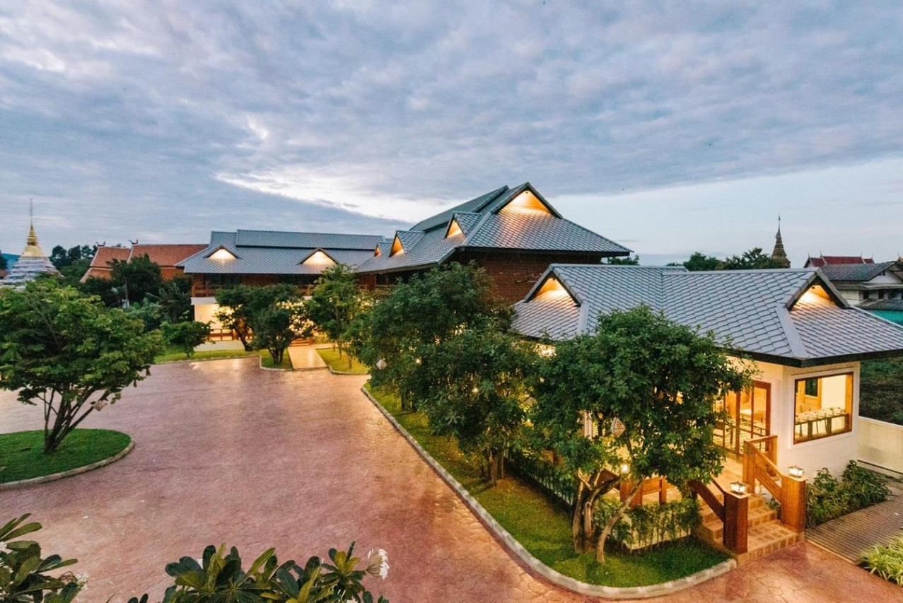 Elevated view of Huen Him Kong's Lanna teak house with gable roofs and golden temple chedis on two sides