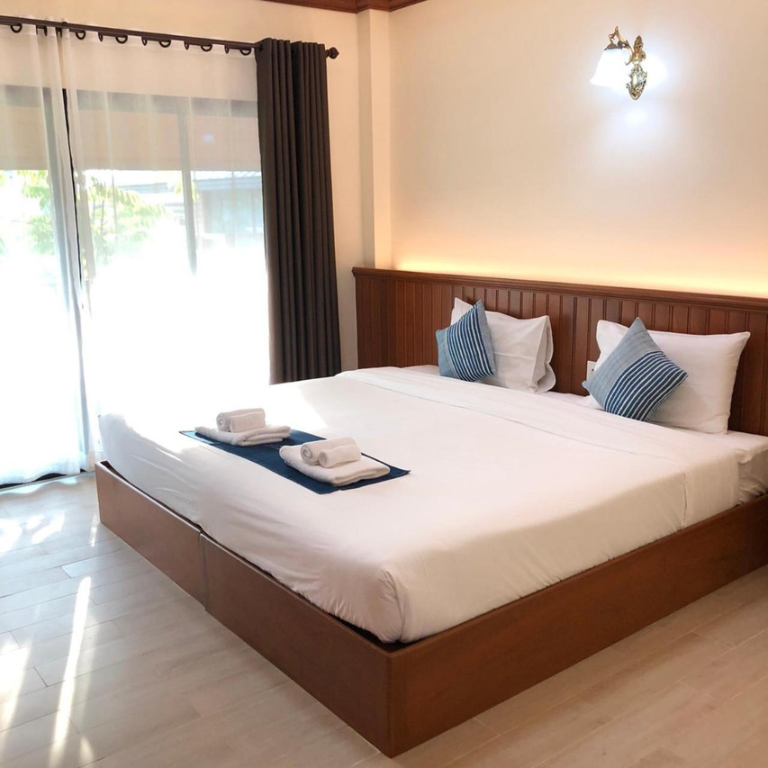 King room with teak-panelled wall, glass door onto a private balcony, wood floor