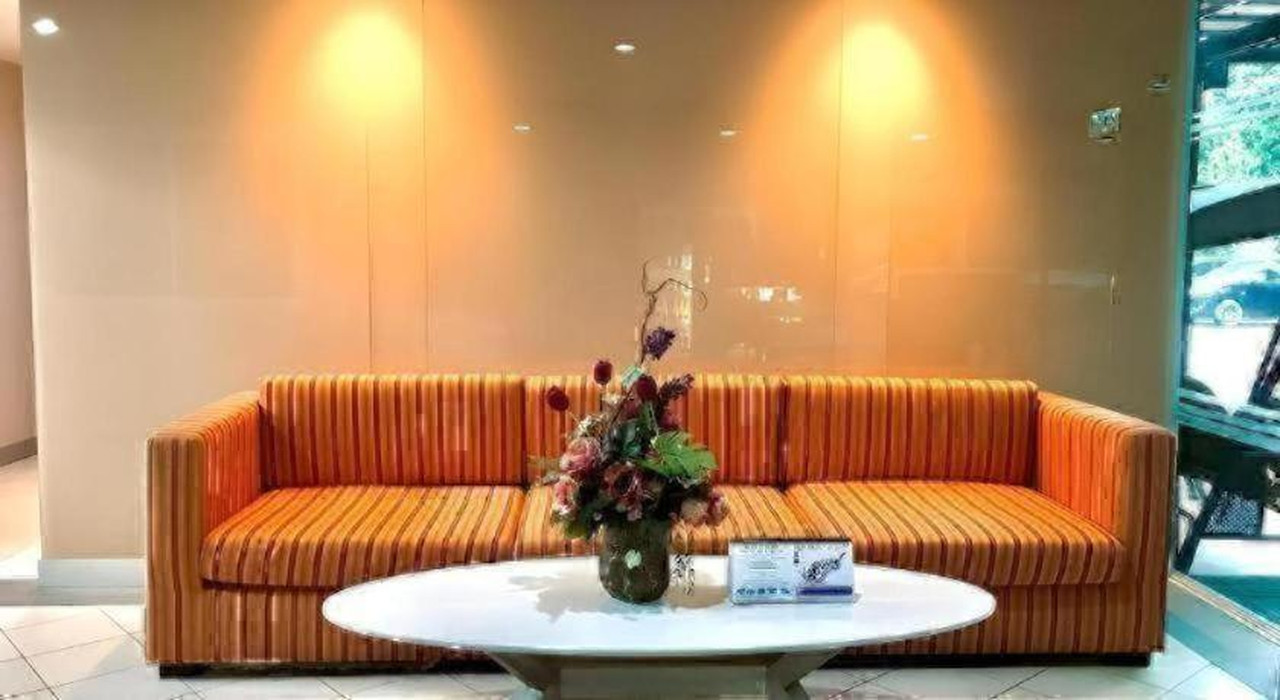 Hotel lobby with an orange striped sofa and a glass wall onto the garden
