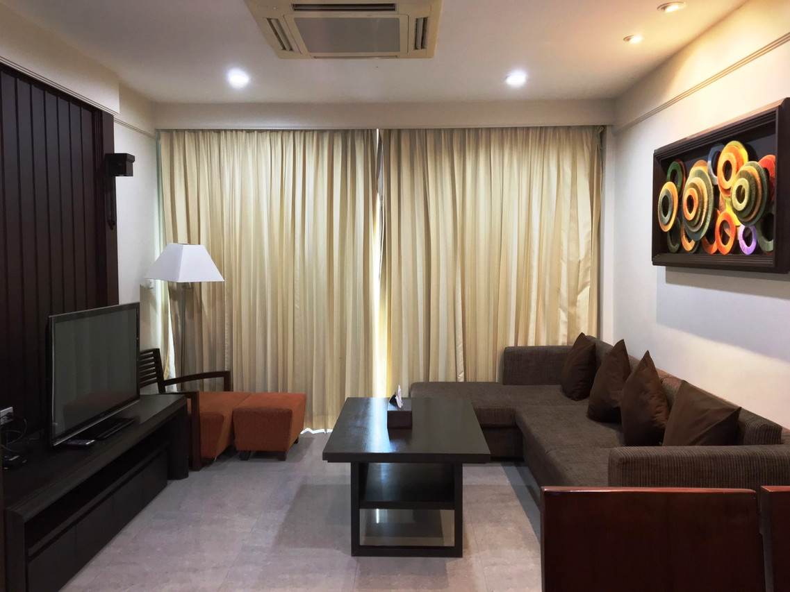 ห้องนั่งเล่นในห้องสวีท โซฟาตัวแอลและงานศิลป์สีสันบนผนัง