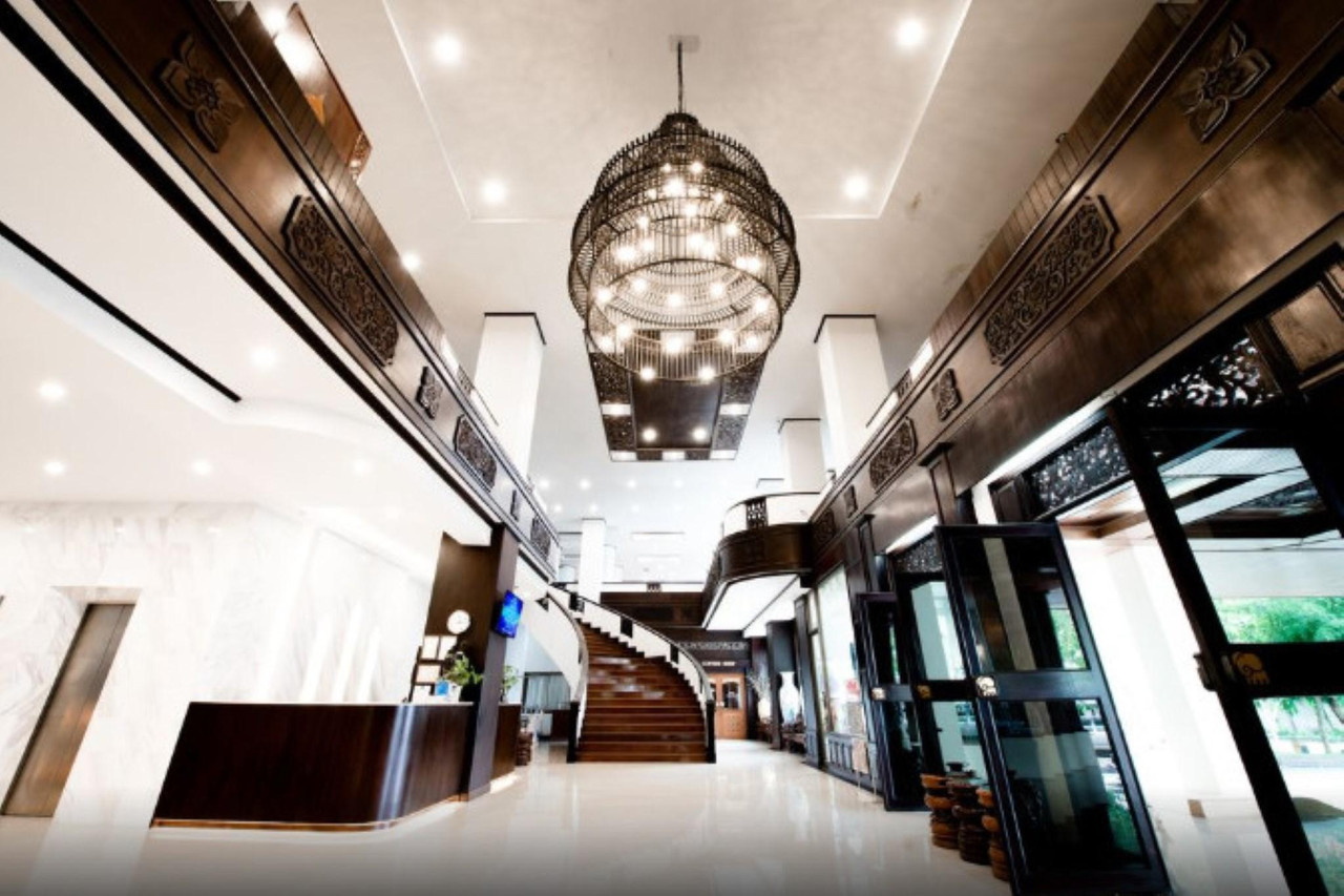 Carved-teak lobby with a large black chandelier at Phrae Nakara Hotel