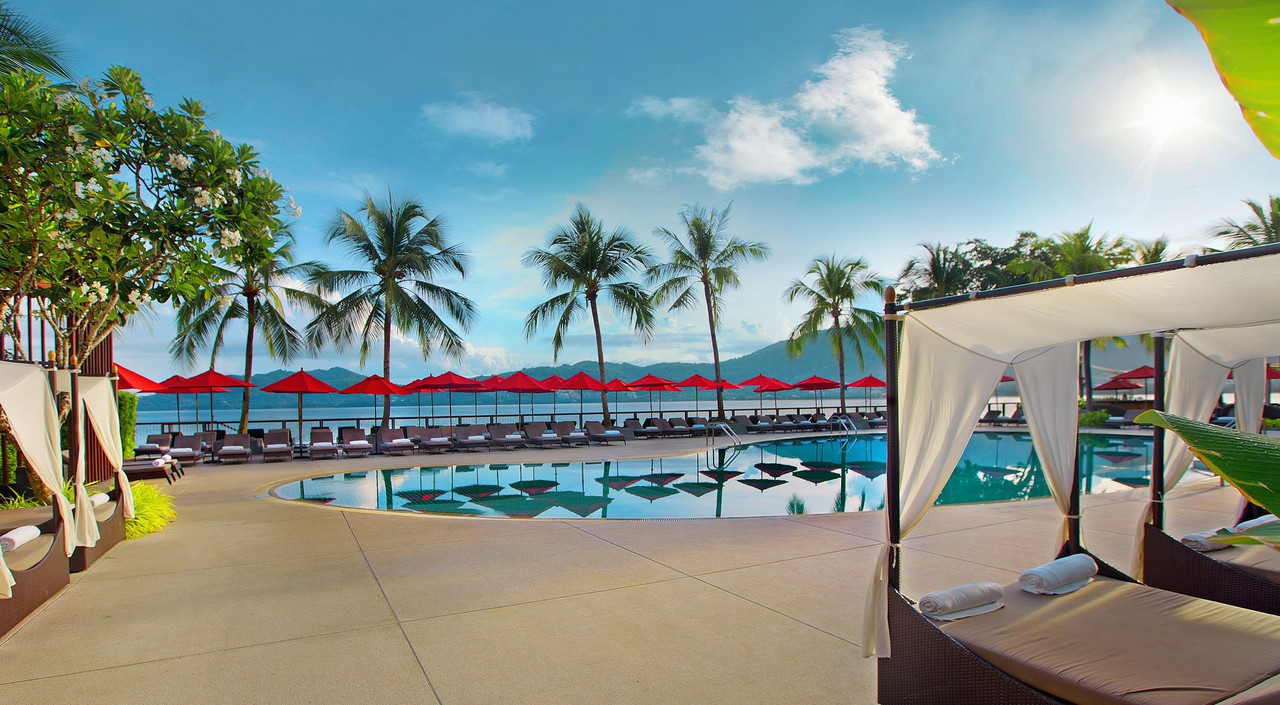 Seafront pool with red umbrellas and Patong Bay views at Amari Phuket