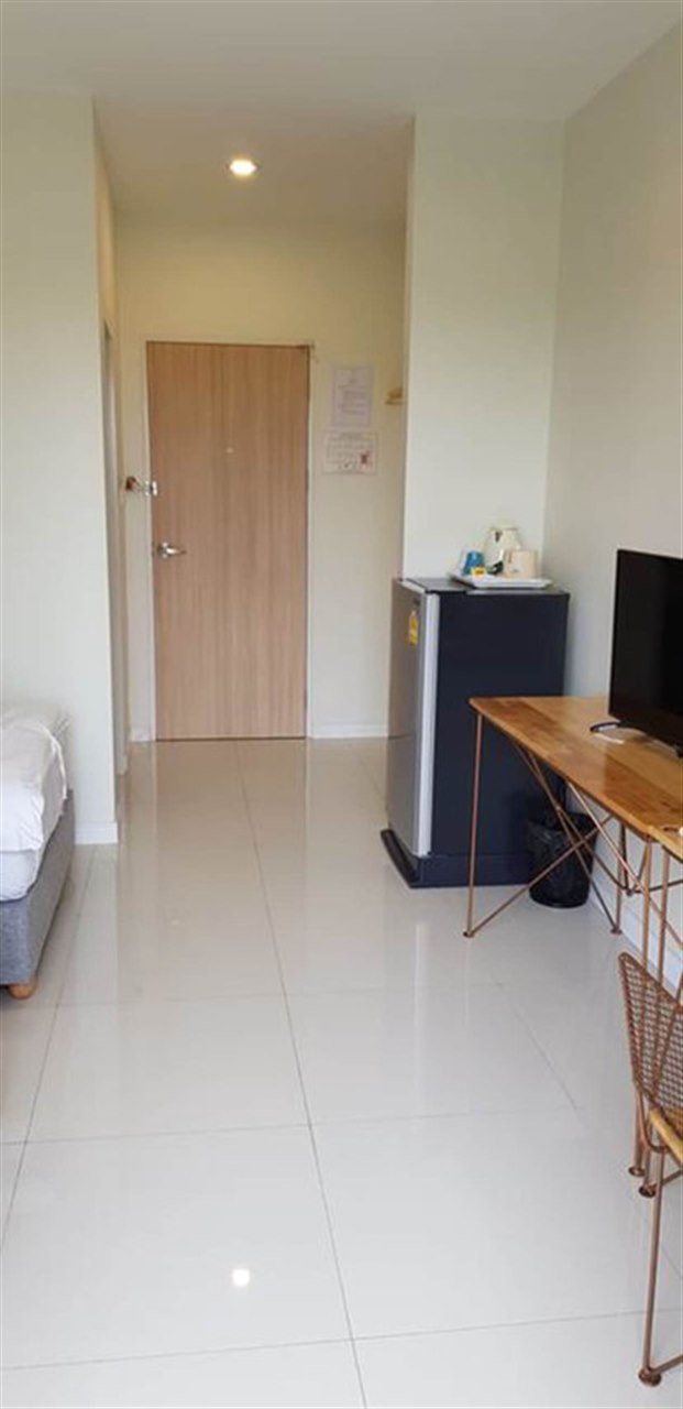 ห้องพัก iRabbit Hotel ปราจีนบุรี เตียงนอน ตู้เย็น และโต๊ะทำงานไม้