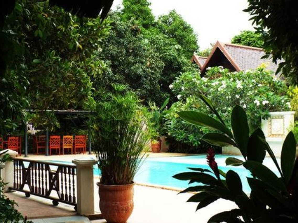 Green garden beside the swimming pool and a Thai-style pavilion at Phuwanalee Resort