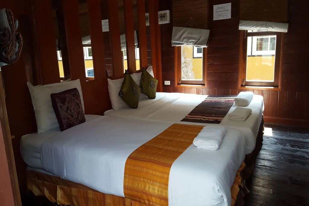 Teak-walled twin cabin room with Thai textile bed runner at Prachuap Garden View Resort