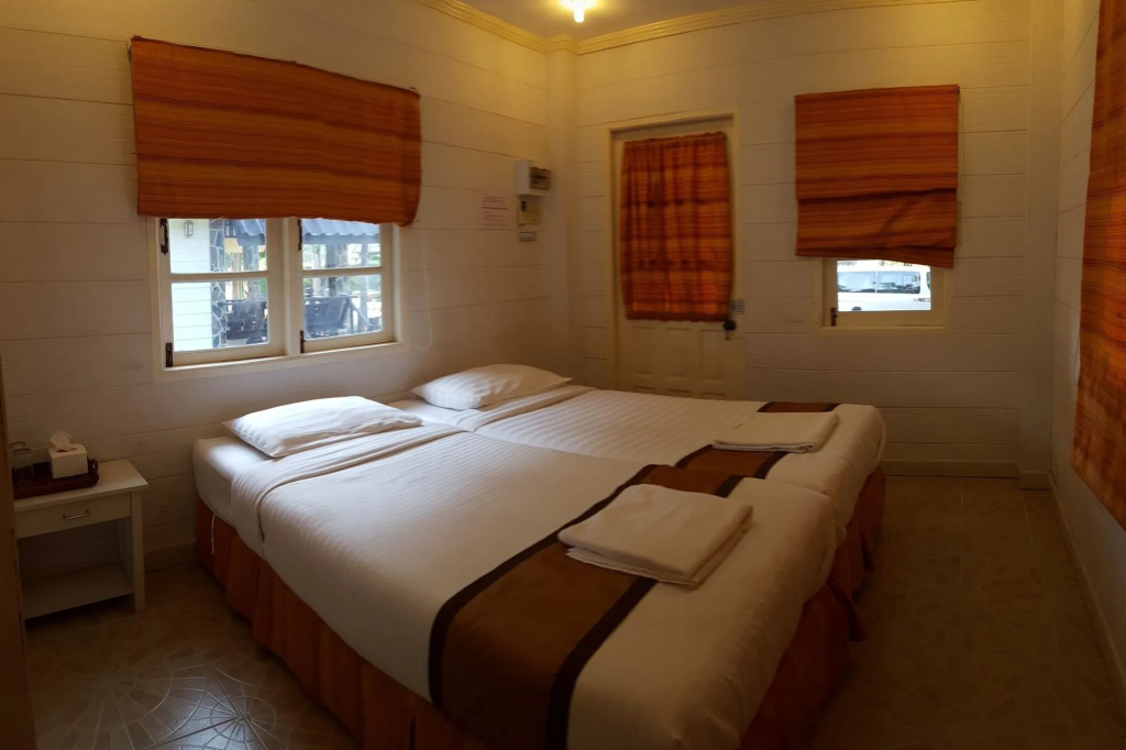 White-walled cabin room with twin beds and a door to the garden at Prachuap Garden View Resort