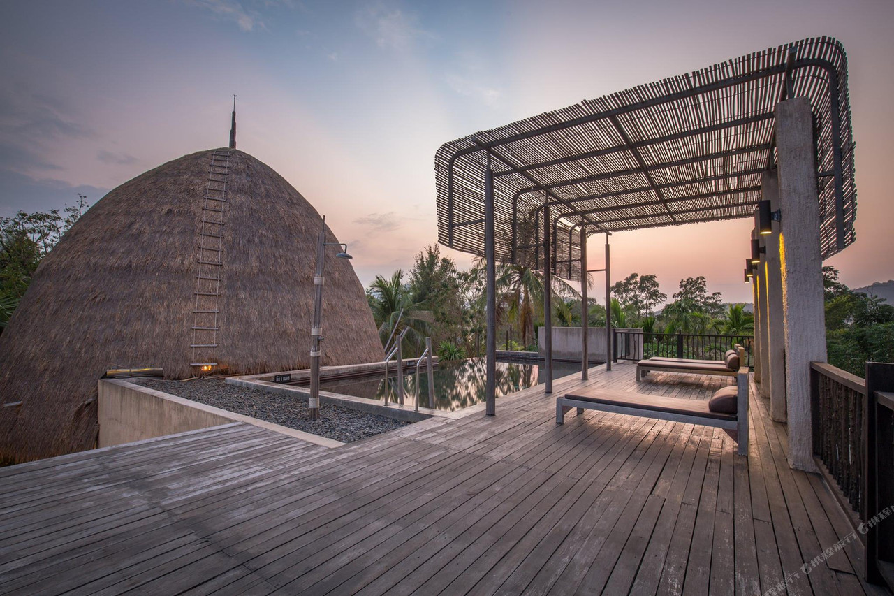 Rooftop pool beside a thatched dome at La a natu at sunset