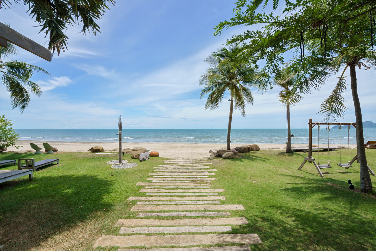 Stone pathway to the private beach with a wooden swing and palms