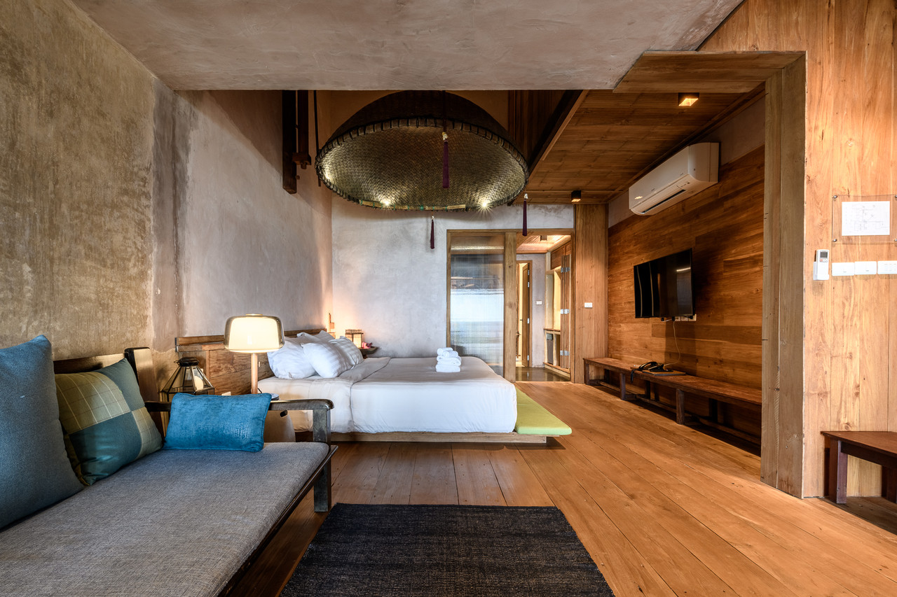 Guest room with earthen walls, teak, and a woven basket light fixture