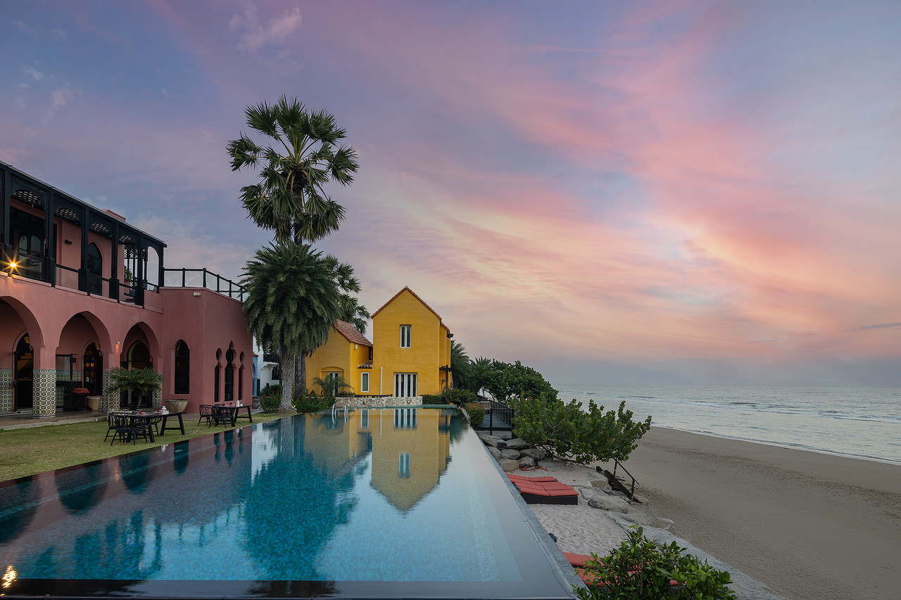 Oceanfront infinity pool at Villa Maroc at sunset with pink and yellow Moroccan buildings
