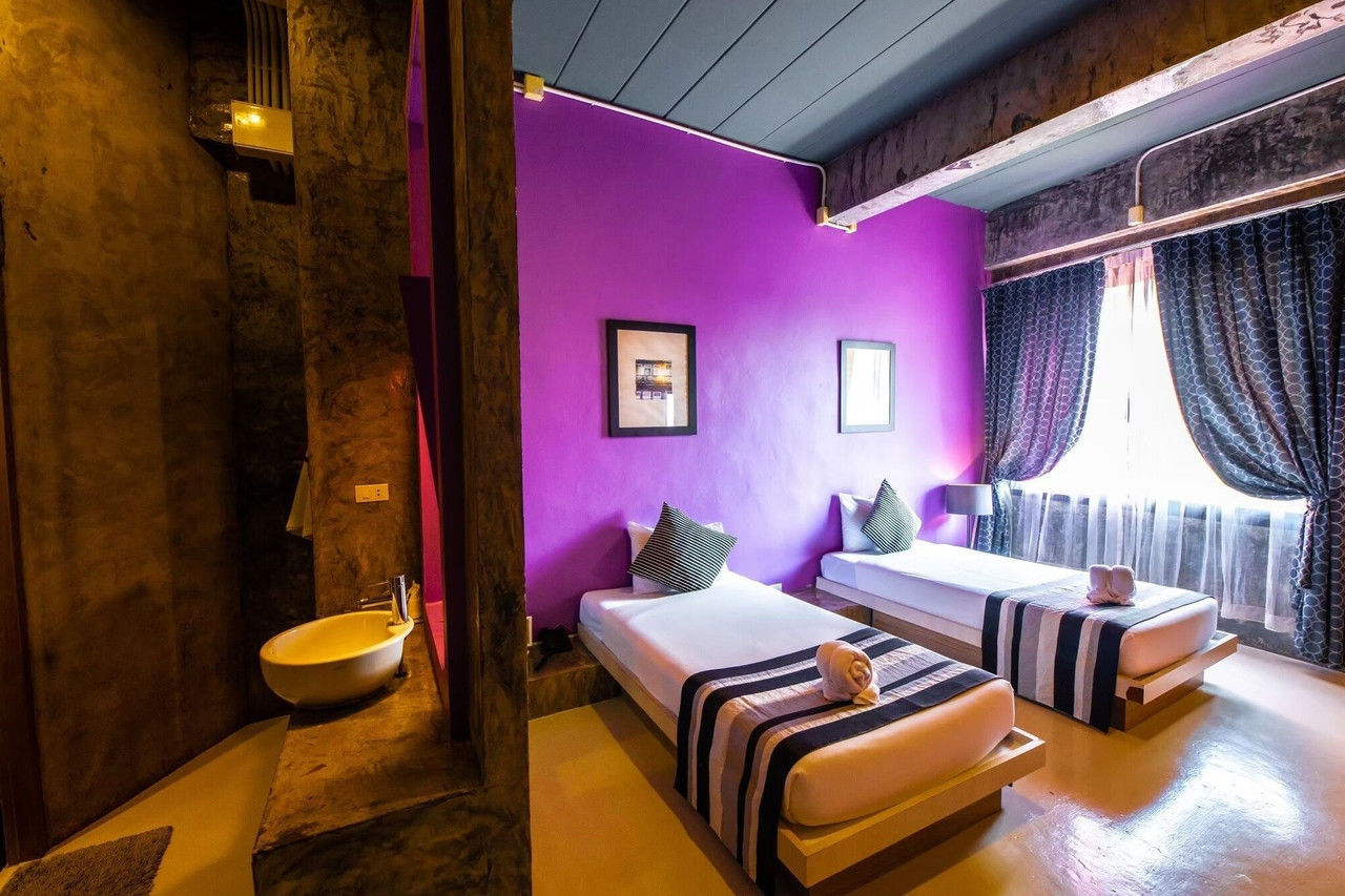 ห้อง Superior Twin ผนังปูนเปลือยทาสีม่วง เตียงแฝดยกพื้น The B Ranong Trend Hotel