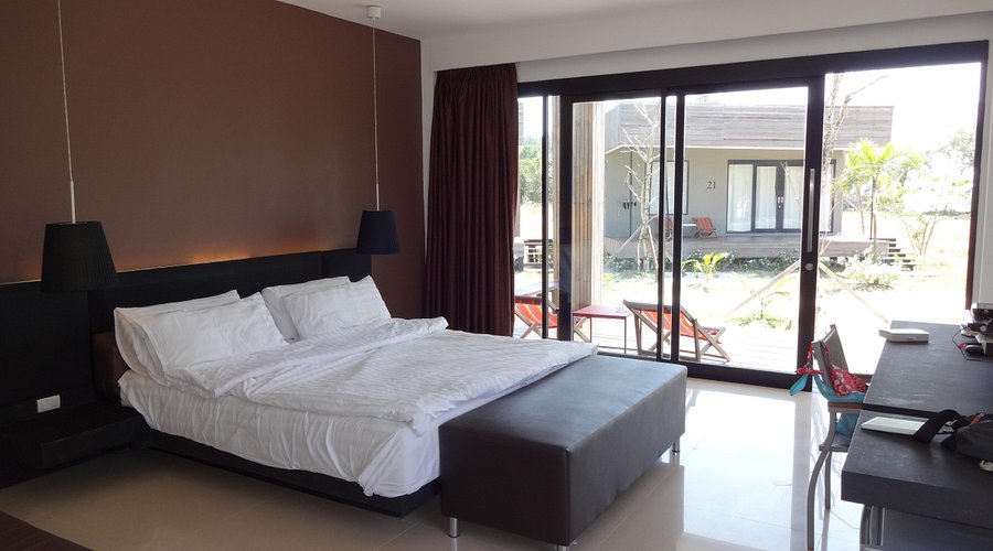 Bungalow interior with a large bed and sliding glass doors opening to the terrace and garden