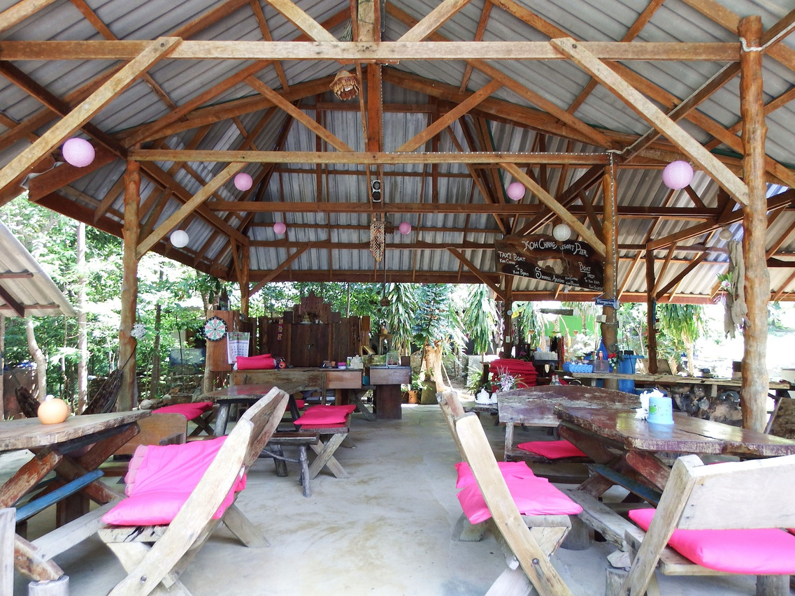 ร้านอาหารเปิดโล่งหลังคาไม้ ม้านั่งไม้เบาะชมพู ริมหาด