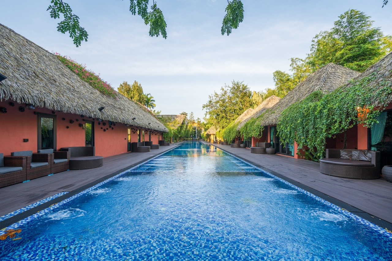 The 70-metre pool flanked by thatched-roof villas at Khum Damnoen Resort