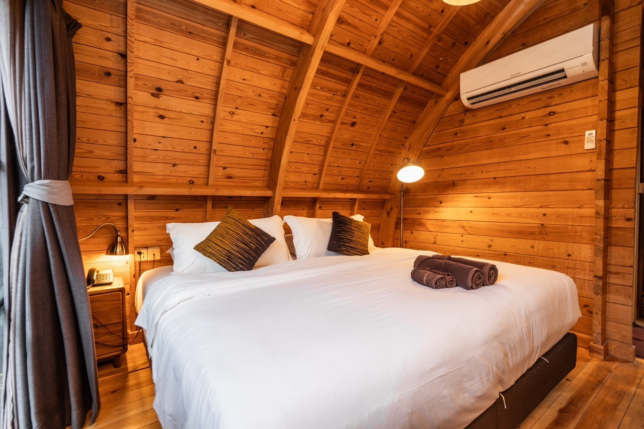 Timber villa interior with a curved pine ceiling and a soft double bed