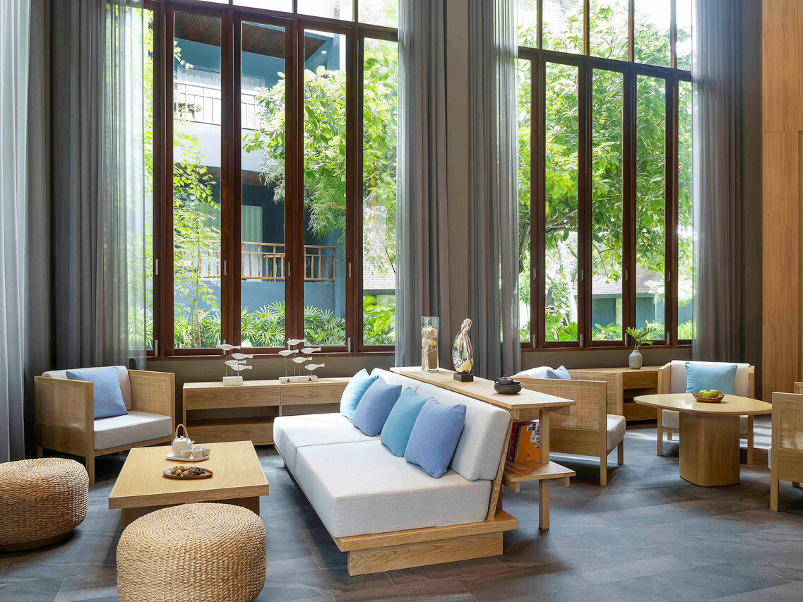 ล็อบบี้เลานจ์เพดานสูงกระจกบานใหญ่มองเห็นสวนของ Mercure Rayong Lomtalay