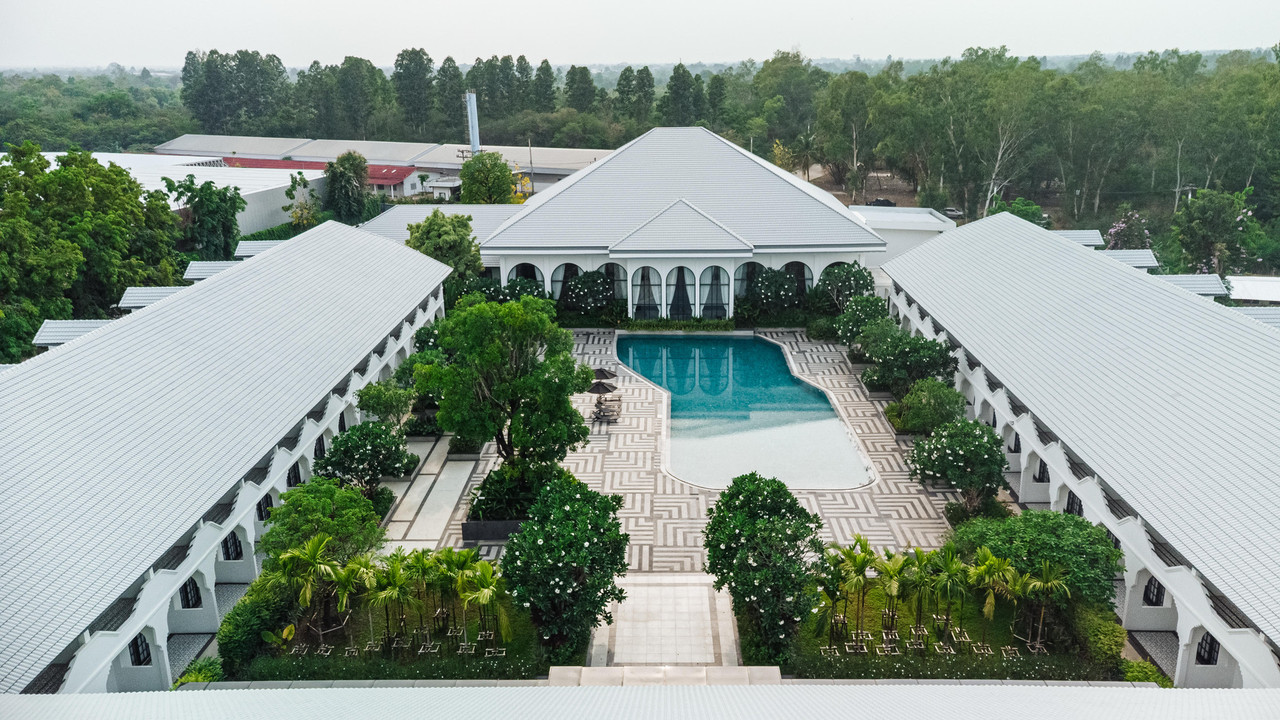 Aerial view of the white twin wings framing the geometric-paved courtyard pool