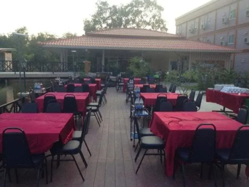 Open-air dining terrace with red-clothed tables beside the canal behind the building