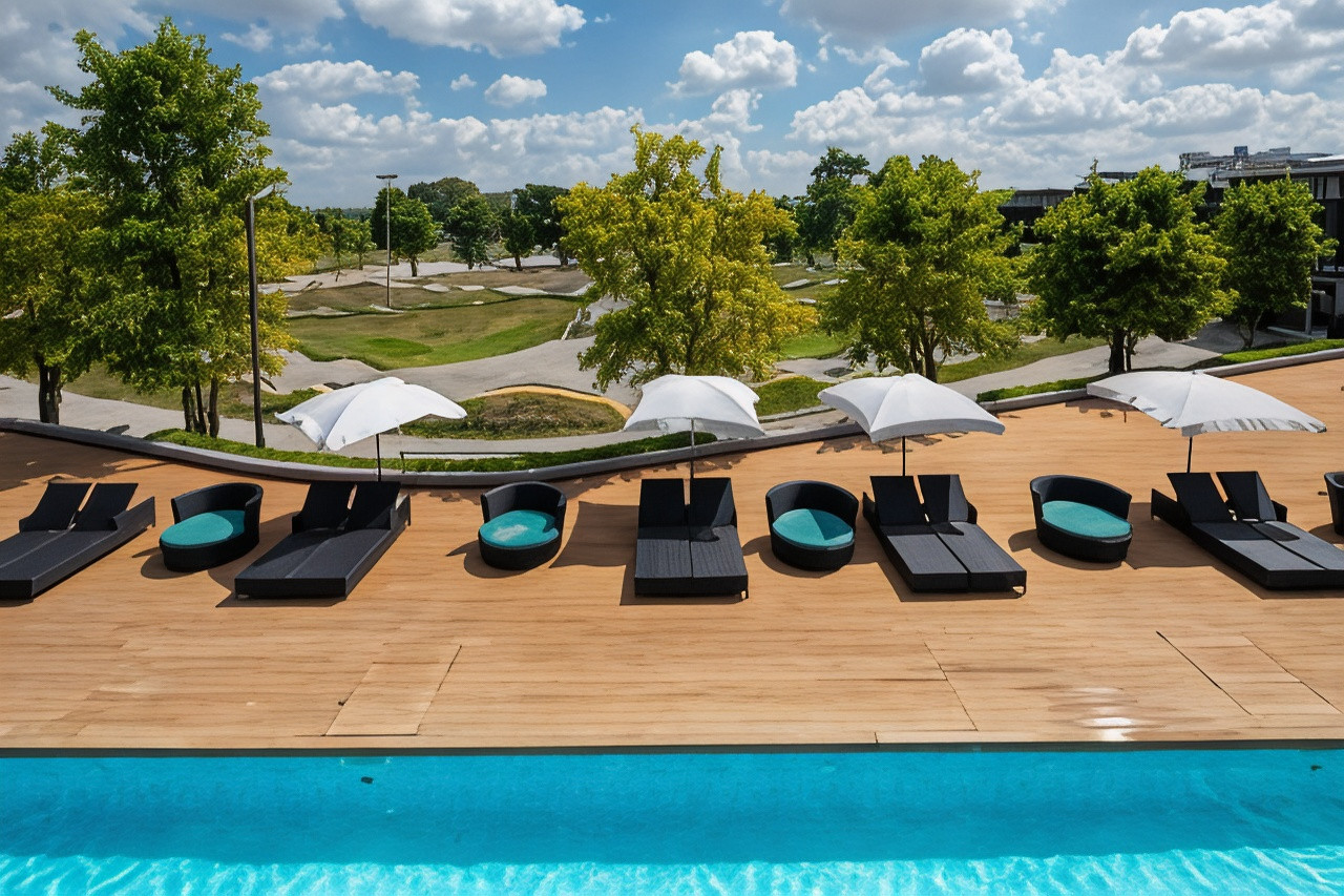 Outdoor pool and sun loungers at The VELO'S Hotel with the pump track behind
