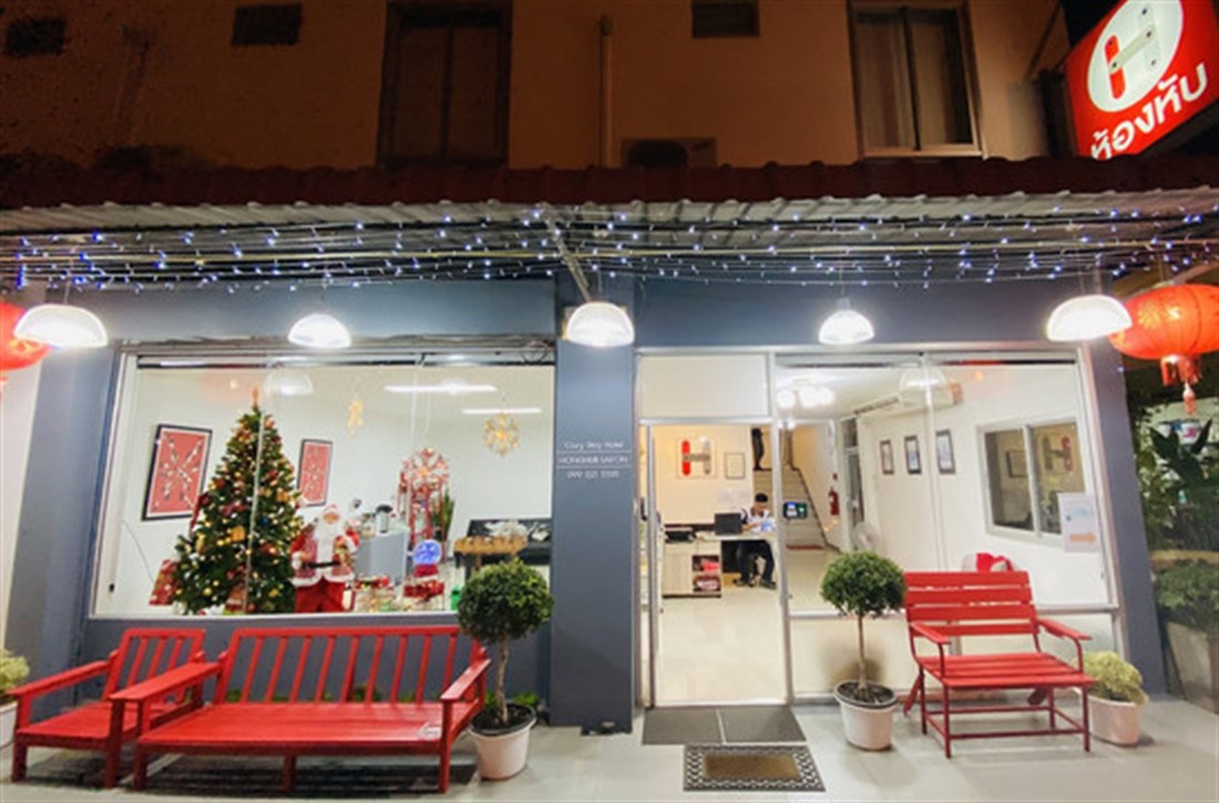 หน้าตึก Honghub Sakon ตอนกลางคืน ป้ายบานพับสีแดงสว่าง มีม้านั่งสีแดง