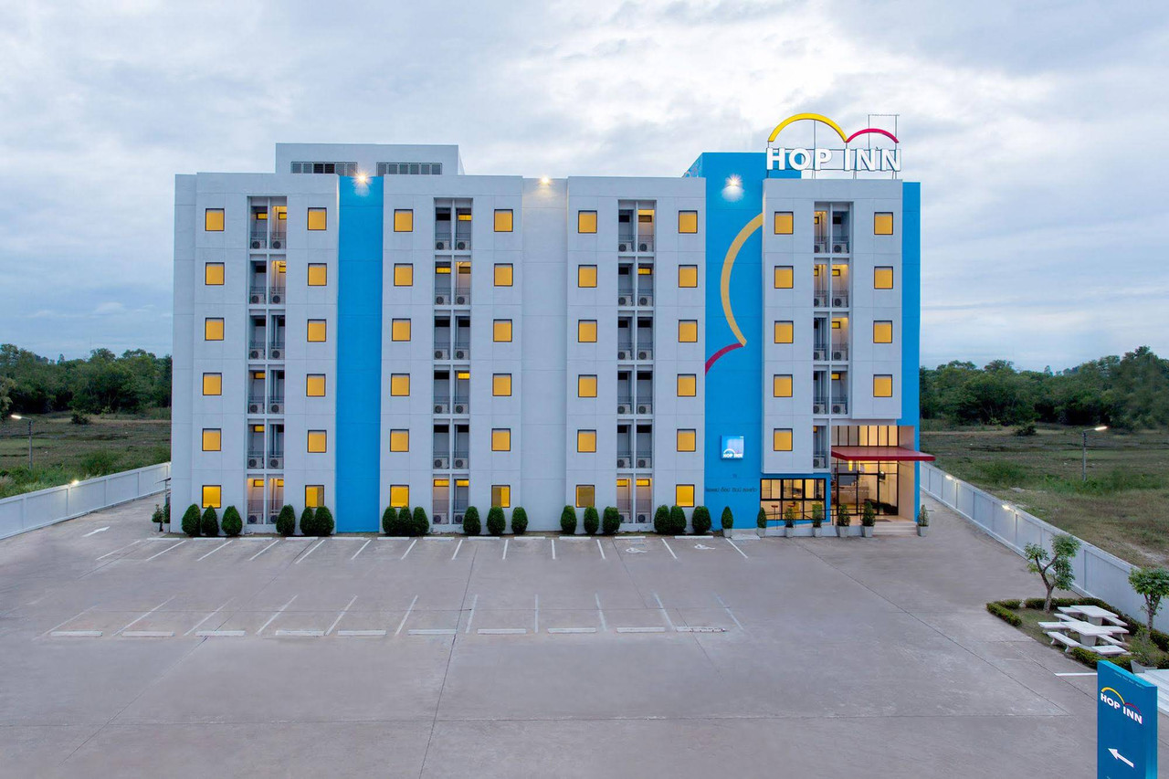 มุมสูงตัวอาคาร Hop Inn Sakon Nakhon ยามเย็นกับลานจอดรถกว้าง