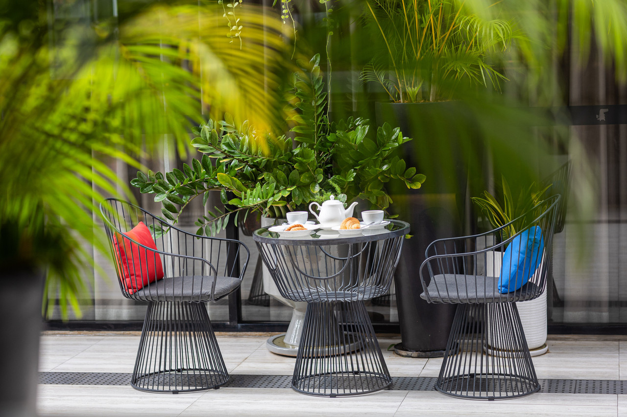 โซนคาเฟ่กลางแจ้งในสวน เก้าอี้เหล็กกับหมอนสีน้ำเงินและแดง