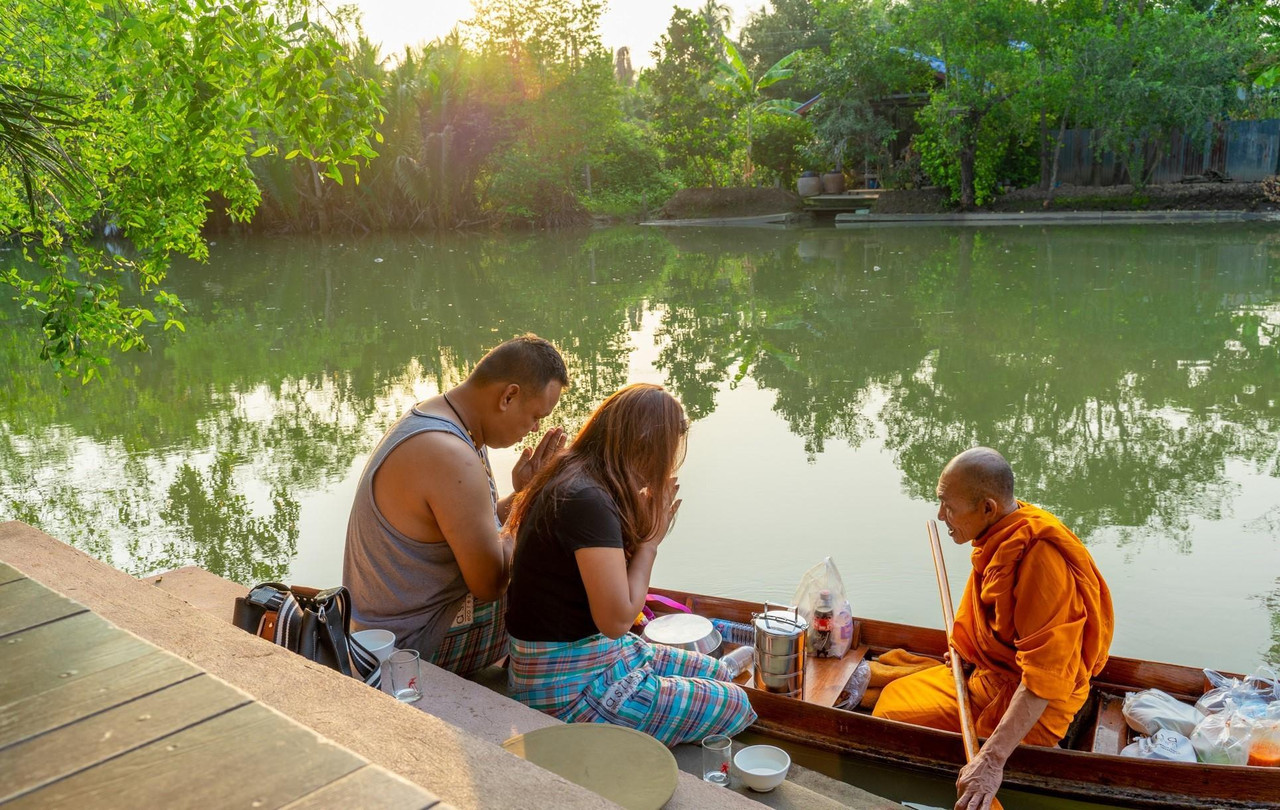 แขกตักบาตรพระทางเรือริมคลองตอนเช้าที่ Asita Eco Resort