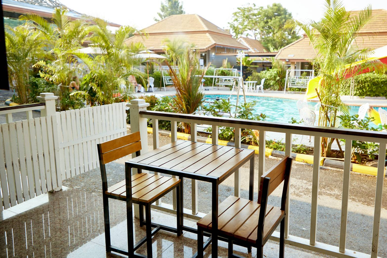 Wooden balcony table looking out over the outdoor pool and bungalows at Baan Dara Resort