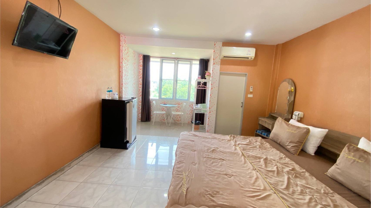 Guest room with terracotta-orange walls, a large bed and a window seating nook