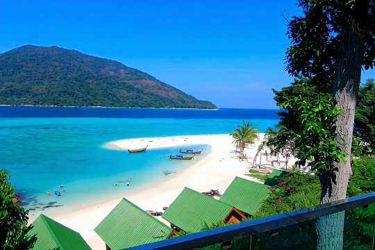 White-sand beach and longtail boats below Mountain Resort Koh Lipe with Koh Adang island beyond